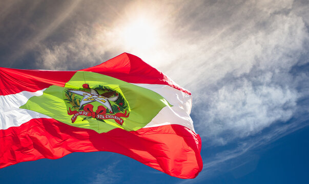 Santa Catarina state flag in Brazil and blue sky with clouds and sun.