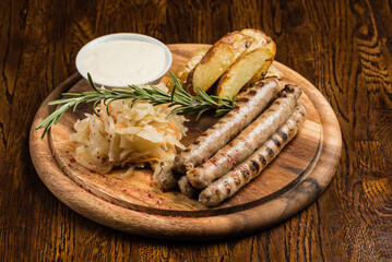 
grilled sausages with sauerkraut and baked potatoes with garlic sauce lunch dinner on a wooden board serving dishes delicious