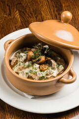 stewed potatoes with mushrooms, vegetables and meat in a clay pot
