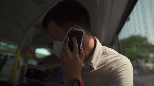 Man sits on bus wearing protective mask ffp2 uses smartphone in Germany, Munich. Passenger in protective mask in public transport and surfing Internet. Coronovirus rules of personal protection 