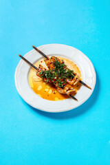 Squid on a skewer with iceberg lettuce shavings and chopped chili