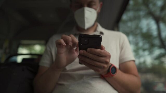 Passenger in ffp2 mask is on bus in Munich, browsing the Internet on mobile phone. Coronovirus regulations in Germany. Personal hygiene. Man on public transport using mobile app. Travel safely 