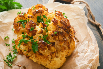 Baked cauliflower. Oven or whole baked cauliflower spices and herbs server on wooden rustic board...