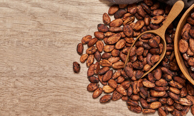 top view or flat lay cocoa seed or cacao beans with wood scoop in wooden table background                                                                                   