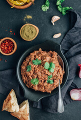 Mashed red bean with spices. Traditional georgian dish lobio in black plate with bread and pickled hot peppers.