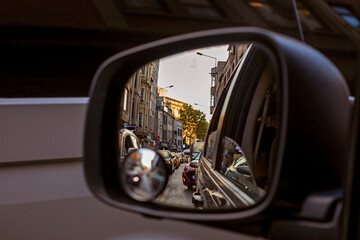 reflection of huge traffic in the left car mirror in the evening at sunset in a city of millions....
