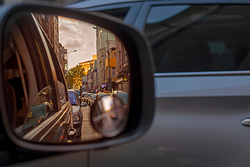reflection of huge traffic in the right car mirror in the evening at sunset in a city of millions....