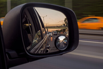 reflection of cars in the right car mirror in the evening at sunset in the capital. Traffic.