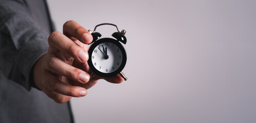 The hand of  businessman man holds the alarm clock. The Concept of Time to work,punctual on time or late.