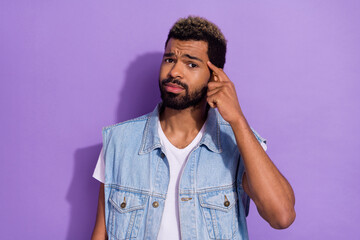 Photo of funky unsure guy dressed denim finger temple forget important thing isolated purple color...