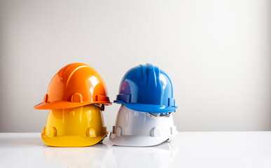 Four construction helmets stacked, safety helmet hat for engineer or worker on white wall background
