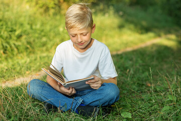 Child boy reading book outside. Concept of back to school, learning.
