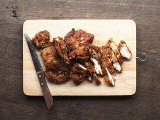 Top view golden brown deep fried chicken sliced on wooden cutting board