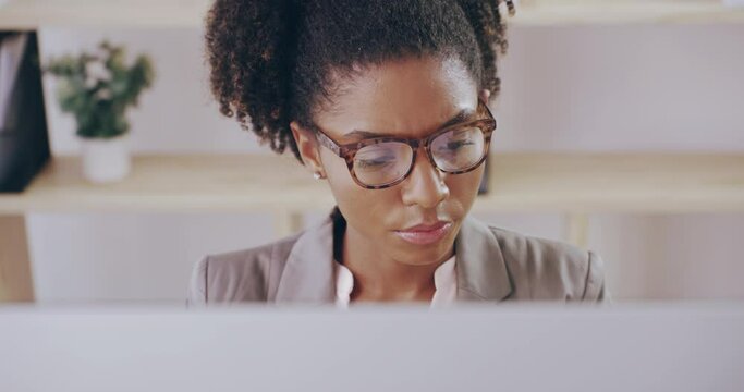 Online journalist working, typing on a computer while reading a document or article in an office. Business woman blogger or reporter doing research for article or paper looking proud with progress
