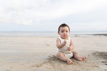 Portrait of a little cute toddler asian girl wearing white bodysuit sitting during summer vacations.
