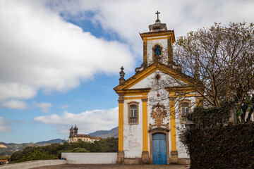 Igrejas de Ouro Preto Minas Gerais em primeiro e segundo plano em meio a montanhas com céu azul e nuvens