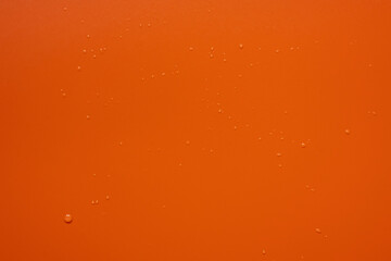 Red background with barely noticeable drops of splashed water on the surface. Copy space. Top view. 