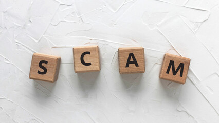 Text SCAM on wooden cubes on white background. Square wood blocks. Top view, flat lay.