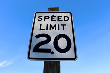 The black and white speed limit with the blue sky.