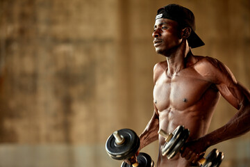 Attractive african american man smiling and doing exercise with dumbbells.