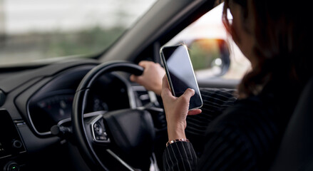 Young woman using smart phone mobile phone in car while driving.