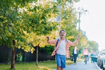 caucasian boy walking to school wearing school bag. Begining of academic year