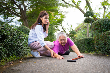 Asian senior woman fell down on lying floor because faint and limb weakness and pain from accident and woman came to help support and call emergency. Concept of old elderly insurance and health care