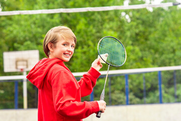 smiling little sportsman playing badminton. joyful child holds a racket from badminton in his hands