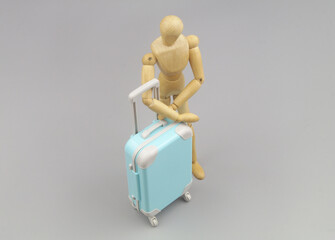 Mannequin with suitcase on gray background