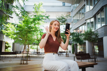 Shot of a student girl doing a video call with her friends at the university campus