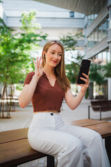 Student young woman greeting in a video call with her friends at the university campus during break