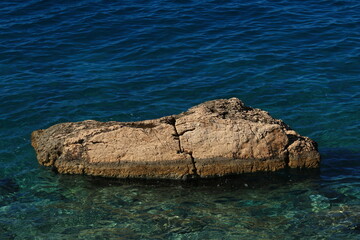 A large rock protruding above the surface of the Adriatic Sea