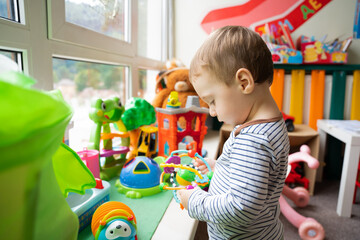 Toddler boy plays with educational toys in the children's room. The study of colors and the...