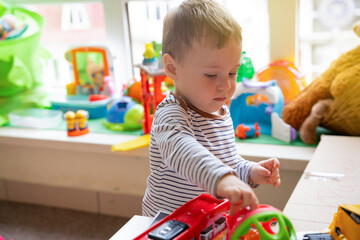 Toddler boy plays with toys in the children's room. Educational toys for young children. Child one and a half years - two years. Selective focus