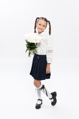 
happy schoolgirl in uniform with a backpack jumping on a white background in the studio. little girl is ready for school.