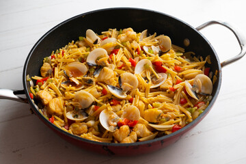 Noodles with monkfish and red peppers. Traditional tapa cooked in paella. Spanish original recipe.