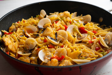 Noodles with monkfish and red peppers. Traditional tapa cooked in paella. Spanish original recipe.