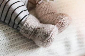 Fototapeta na wymiar Baby booties tied by hands for a newborn baby. Close-up of children's legs in knitted socks