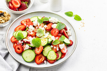 Refreshing cucumber strawberry  cheese salad  balsamic dressing on plate. Top view, flat lay, copy space.