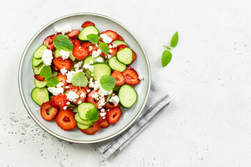 Low carb healthy cucumber strawberry goat cheese salad on plate. Top view, flat lay, copy space.