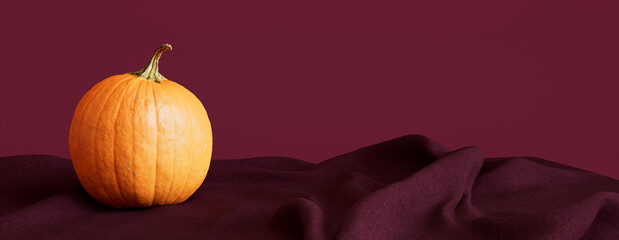 Pumpkin with Burgundy colored Fabric. Fall themed Background with copy-space.