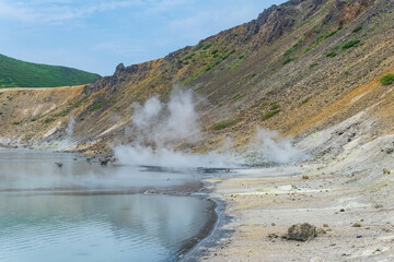 hot mineralized lake with thermal spring and smoking fumaroles in the caldera of the Golovnin volcano on the island of Kunashir