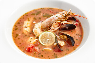 Tomato seafood soup in plate isolated on white background. Seafood stew Cioppino - shrimp,  mussels and salmon in tomato broth. Seafood dish in Italian restaurant menu.