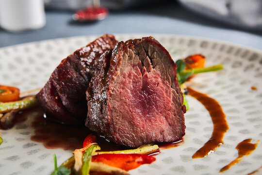 Roasted Beef fillet with vegetables. Roasted Mignon steak with paprika and celery. Beef tenderloin with garnish. Beef steak medium rare doneness. Delicious meat menu. Dish concept with angus beef.