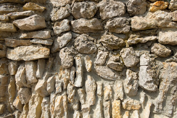 Natural stack rock stone wall building facade with deep shadows in natural sunlight