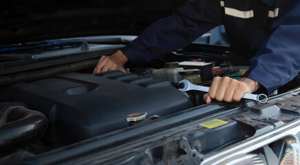 Obraz premium Repairman wearing work gloves holding a wrench and engine