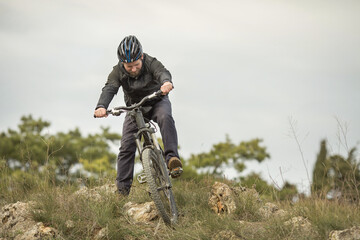 Obraz premium a young man in a bicycle helmet rides down the mountain on a mountain bike