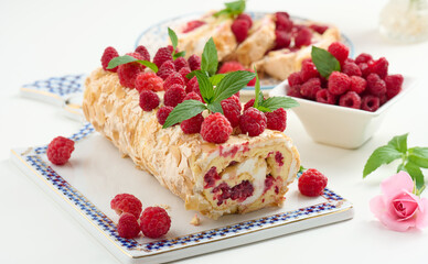 Baked meringue roll with cream and fresh red raspberry on a white board,