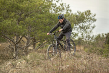 Fototapeta na wymiar a young man in a bicycle helmet rides down the mountain on a mountain bike.