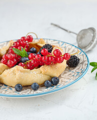 Fruit tart with red currants sprinkled with powdered sugar on a white table